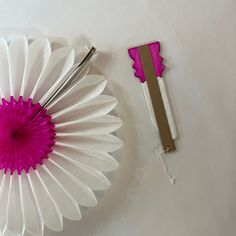 a pink and white paper flower next to a pair of scissors