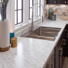 a kitchen with marble counter tops and stainless steel sink faucet next to window