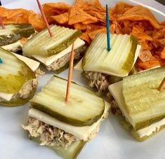 several sandwiches with pickles, cheese and chips on a plate