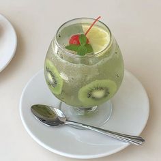 a drink with kiwis, lemon and mint on a white plate