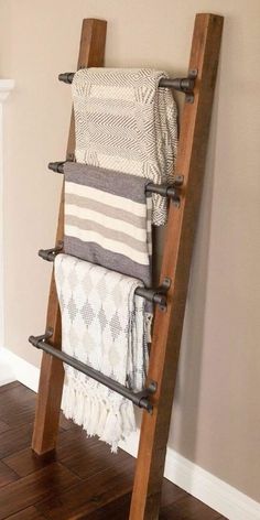 a wooden ladder holding towels and blankets on top of a hard wood floor next to a fireplace