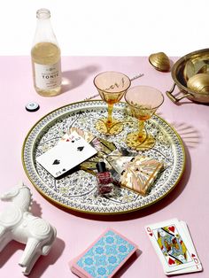 a tray with cards, wine glasses and other items on it next to a bottle