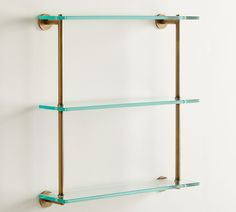 two glass shelves on the wall with brass handles