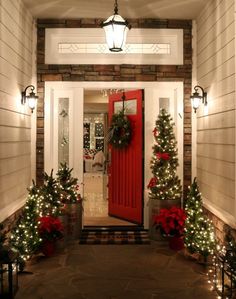 a red front door decorated with christmas wreaths and lights