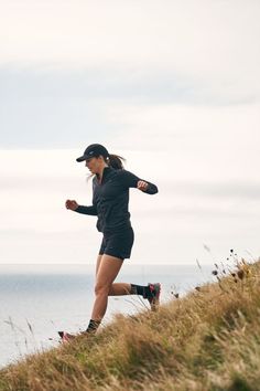 a woman running up a hill near the ocean