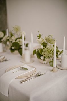 the table is set with white flowers and silverware