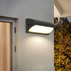 an outdoor wall light on the side of a building at night and in front of a door