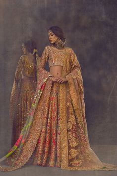 a woman in a gold and red bridal gown with her hands on her hips