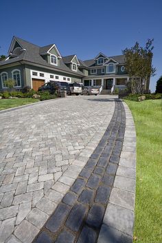 a brick driveway in front of a large house