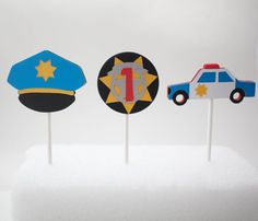 three cupcake toppers in the shape of police cars