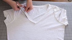 someone cutting up a t - shirt with scissors on top of a piece of paper