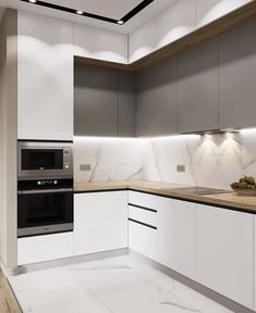 a modern kitchen with marble counter tops and white cabinets, along with an oven in the center