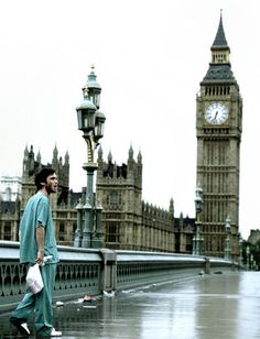 a man in scrubs is walking on the sidewalk near big ben and the palace of westminster