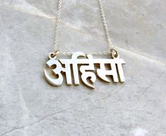 a necklace with the word india written in two different languages, on a marble surface