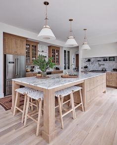 a large kitchen with wooden cabinets and marble counter tops, along with two stools