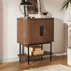 a wooden cabinet sitting on top of a hard wood floor next to a potted plant