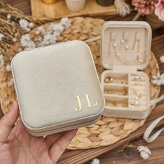 a person holding an open jewelry box with the initials jl on it and flowers in the background