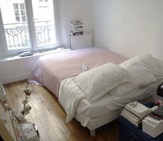 a bed sitting in a bedroom next to a window with a pink blanket on top of it