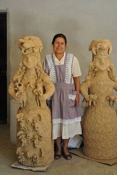 a woman standing in front of some clay sculptures that look like women with heads on their backs