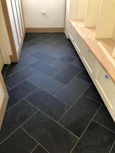 an empty bathroom with black tile flooring and white cabinetry on the wall above