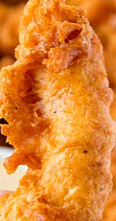 a fried chicken nugget being held up to the camera with dipping sauce in it