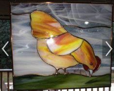 a stained glass bird sitting on top of a fence