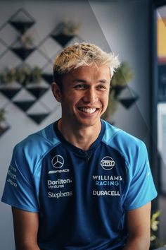 a smiling man in a blue shirt sitting down