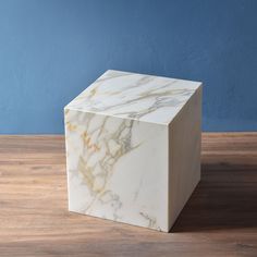 a white marble block sitting on top of a wooden floor next to a blue wall