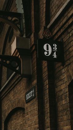 an exit sign on the side of a brick building next to a street light and clock