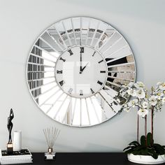 a large round mirror mounted to the side of a wall next to a vase with flowers