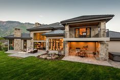 a large house that is in the middle of some grass with mountains in the background