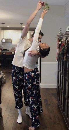 two people are doing yoga in the living room with christmas decorations on the wall behind them