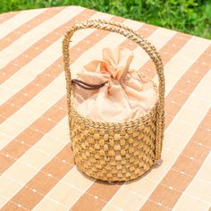 a small basket sitting on top of a checkered table cloth covered table with grass in the background