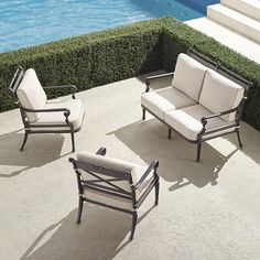 three patio furniture sitting next to a swimming pool