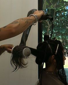 a woman blow drying her hair while another person watches