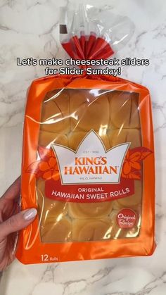 someone holding up a bag of hawaiian sweet rolls in front of a marble counter top