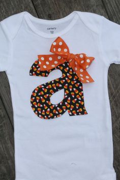 a white shirt with orange and black polka dots on the letter s is decorated with a bow