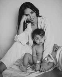 a woman holding a baby on top of a bed