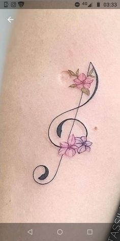 a music note tattoo with flowers on it