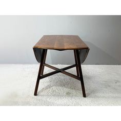 a small wooden table sitting on top of a white carpeted floor next to a wall