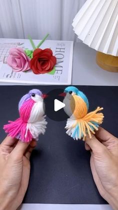 two small birds made out of yarn sitting on top of a table