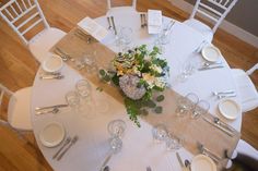 the table is set with white linens and silverware for an elegant centerpiece