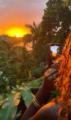 a woman is taking a photo with her cell phone in the jungle at sunset or dawn