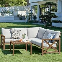 a couch and coffee table on the grass in front of a house with a pool