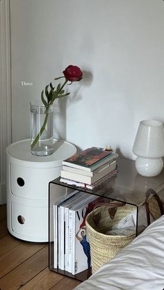 a vase with a flower on top of a table next to a lamp and books