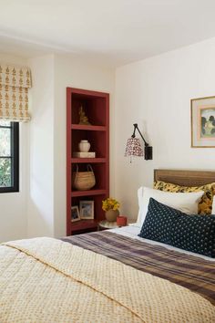 a bedroom with a bed, bookcase and window in the corner next to it