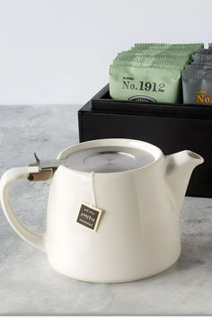 a white tea pot sitting on top of a table next to a box of tissues