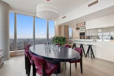 a dining room table with purple chairs in front of a large window overlooking the city