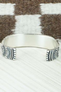 This sterling silver bracelet was made by Navajo silversmith Jerrold Tahe. The inside is signed J. Tahe and stamped sterling.Size: 6" (will fit up to a 7 1/2" wrist)Gap: 1 1/2"Width: 3/4"Free shipping on all orders! We ship with USPS and always include tracking. All orders ship within a day of payment.Returns are accepted up to 30 days after you receive your order. Just send us a message. Our shop offers cash back or store credit. The item must be returned in new condition. Silver Artisan Bracelet, Southwestern Silver Cuff Bracelet, Sterling Silver Inlay Bracelets In Silver Color, Sterling Silver Southwestern Round Cuff Bracelet, Southwestern Sterling Silver Round Cuff Bracelet, Artisan Silver Bracelets With Inlay, Artisan Sterling Silver Bracelet With Inlay, Southwestern Sterling Silver Stamped Bangle Bracelet, Southwestern Style Stamped Sterling Silver Bangle