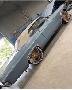 an old blue car parked in a garage